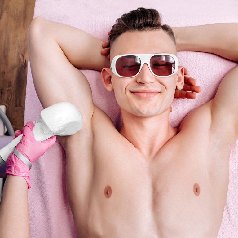 A man is undergoing laser hair removal in a spa salon. The uncle has his hair removed in the armpit area. A young man in a beauty salon lies and smiles during the procedure.